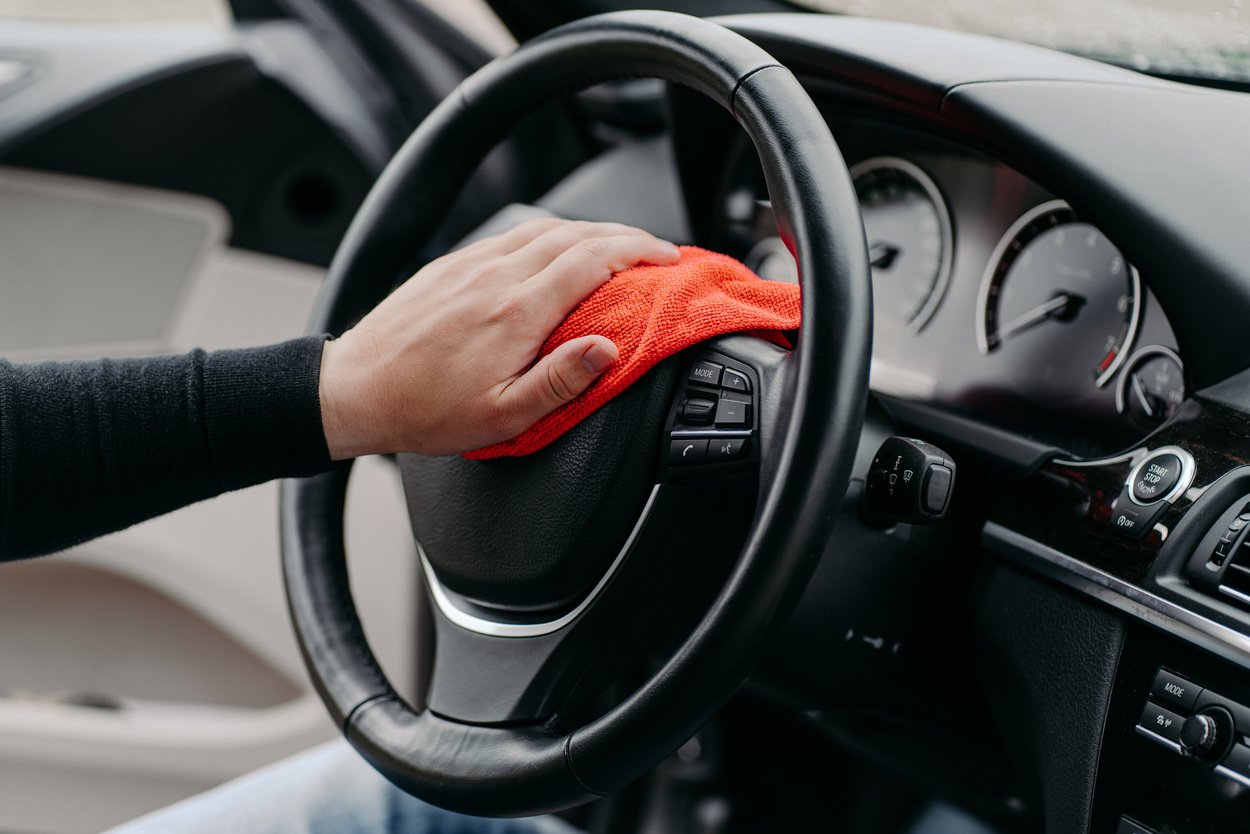 Close up Shot of Mans Hand Cleaning Car Steering Wheel with Microfiber Cloth. Hygiene Prevention during Coronavirus Outbreak